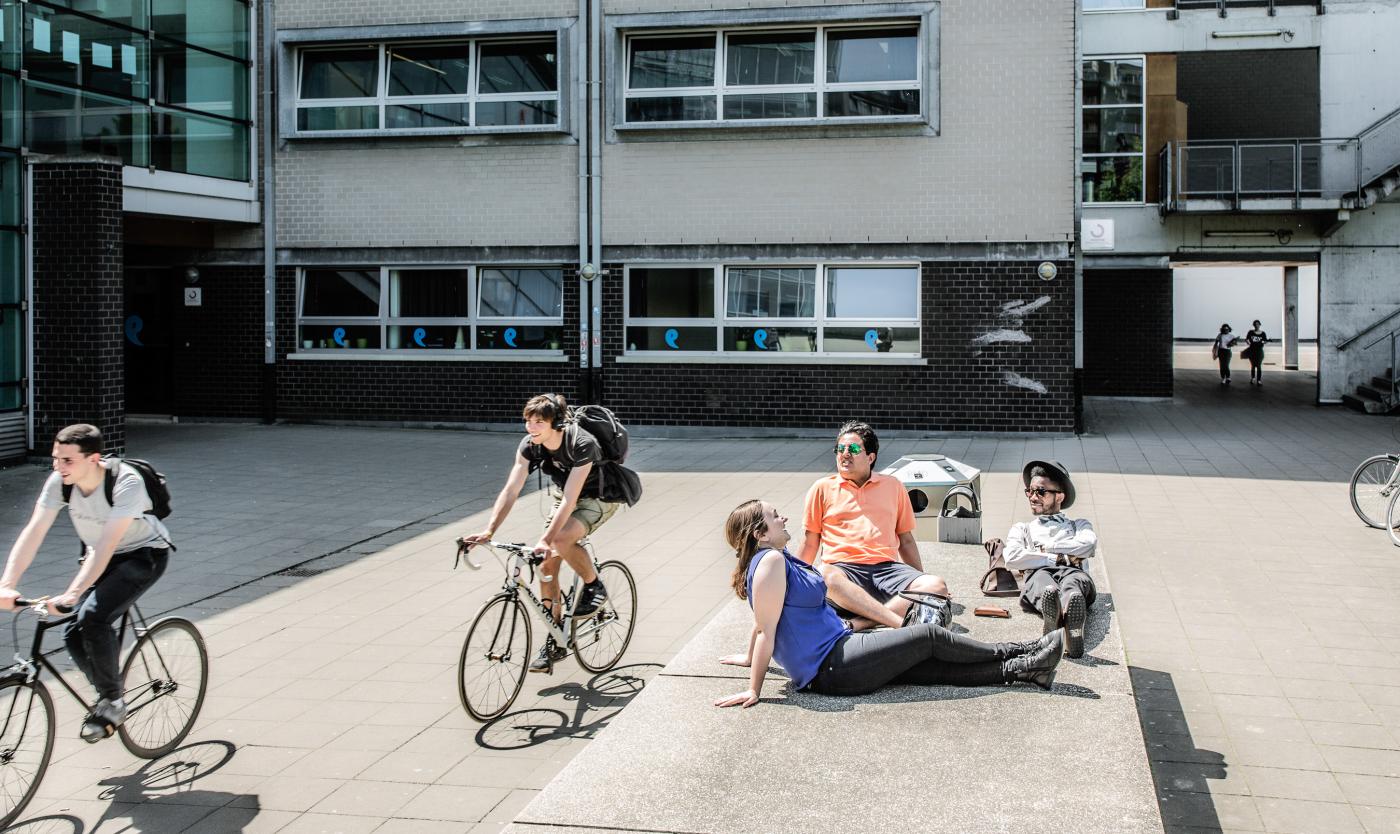 Studenten en fietsers op de esplanade aan het gebouw D op Campus Etterbeek