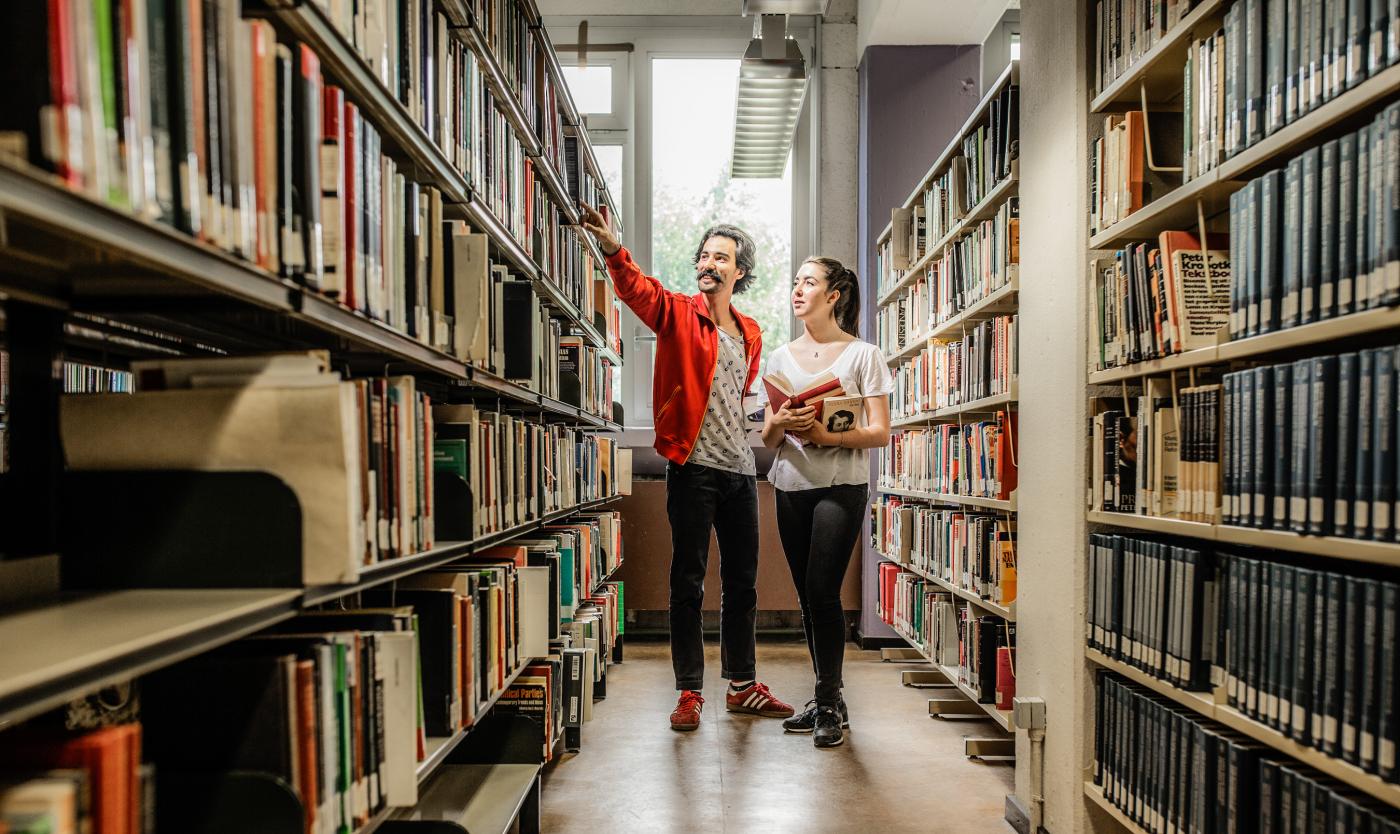 Studenten in bibliotheek aanwijzen een boekenkast op campus Etterbeek