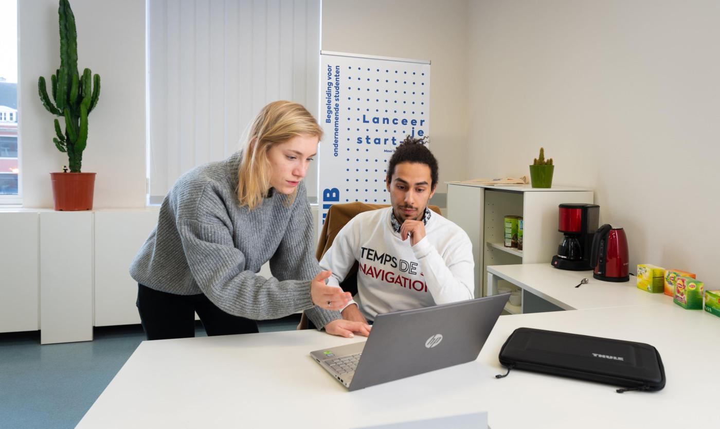 Student en studente kijken naar een scherm aan een bureau