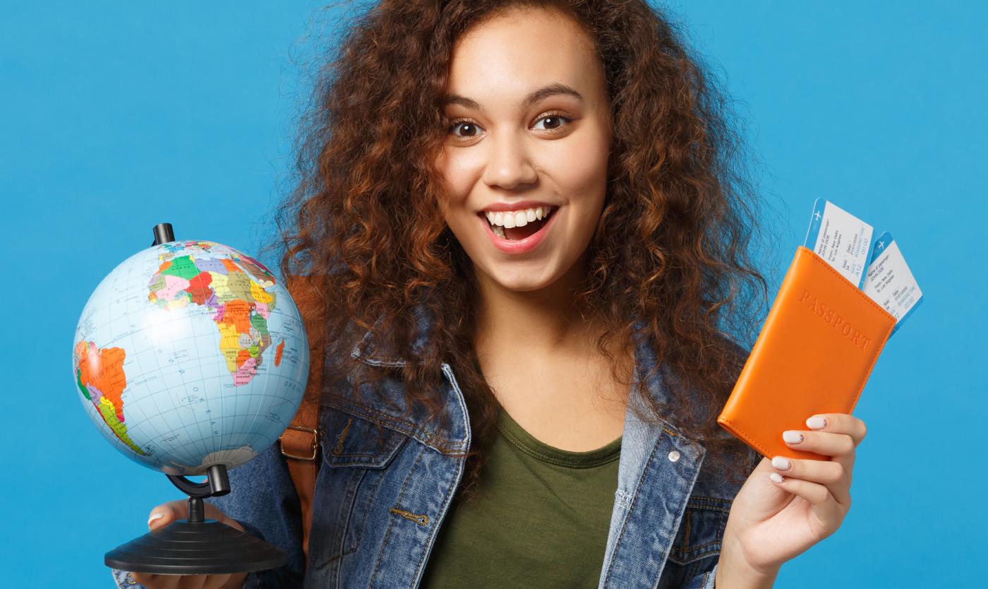 Vrouwelijke studente met paspoort en wereldbol in de hand