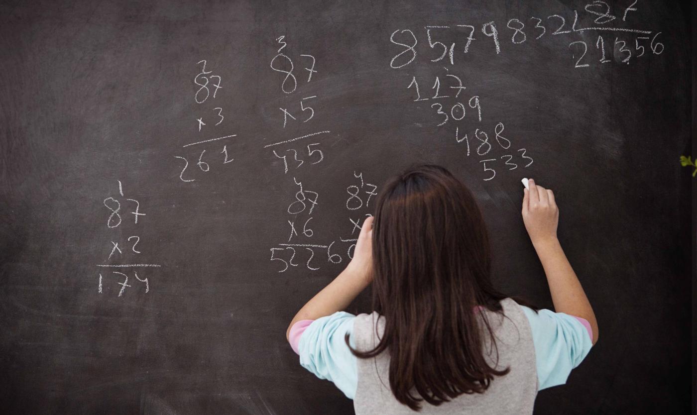 2022_Leerling die wiskunde leert en op een schoolbord schrijft_Klaslokaal met schrijfbord_S_159863552