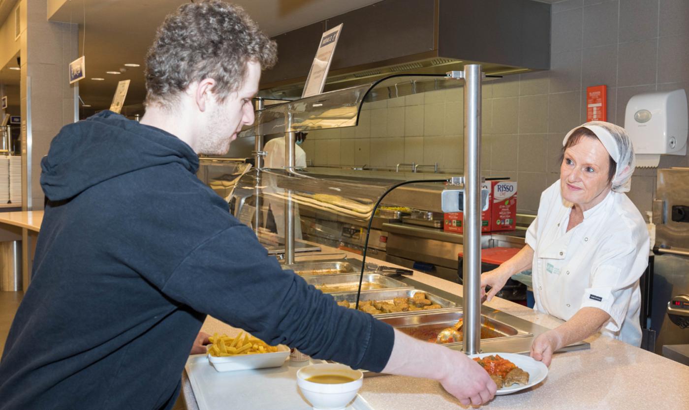2022_Man in resto neemt eten aan van keukenpersoneel_VUB Resto_Etterbeek
