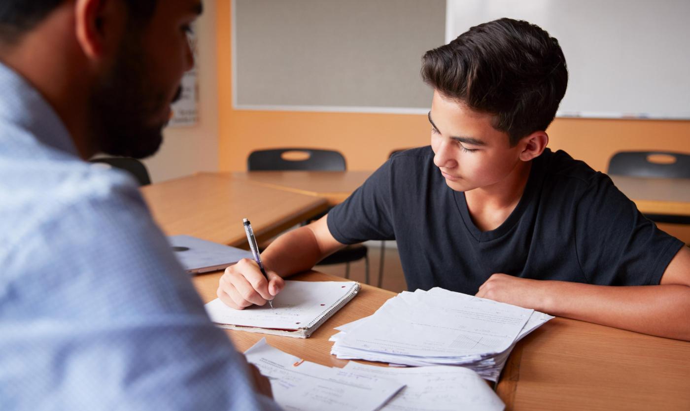 2022_Middelbare schoolleraar die mannelijke student één-op-één collegegeld geeft_Klaslokaal_S_1127431514