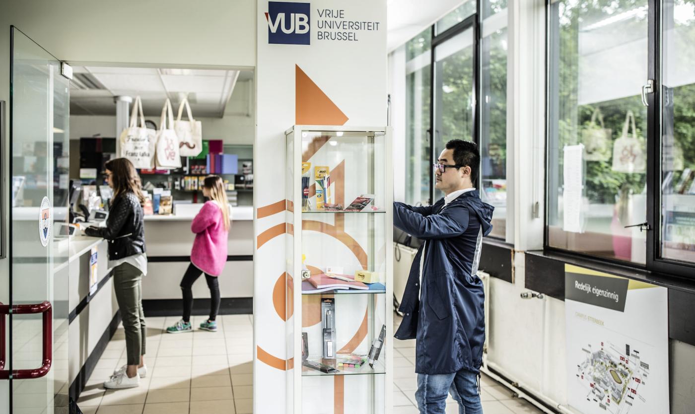 2017_Cursusmateriaal in glazen etalage_Standaard Student Shop_Etterbeek_VUB Student bekijkt cursusmateriaal in glazen etalage in Standaard Student Shop