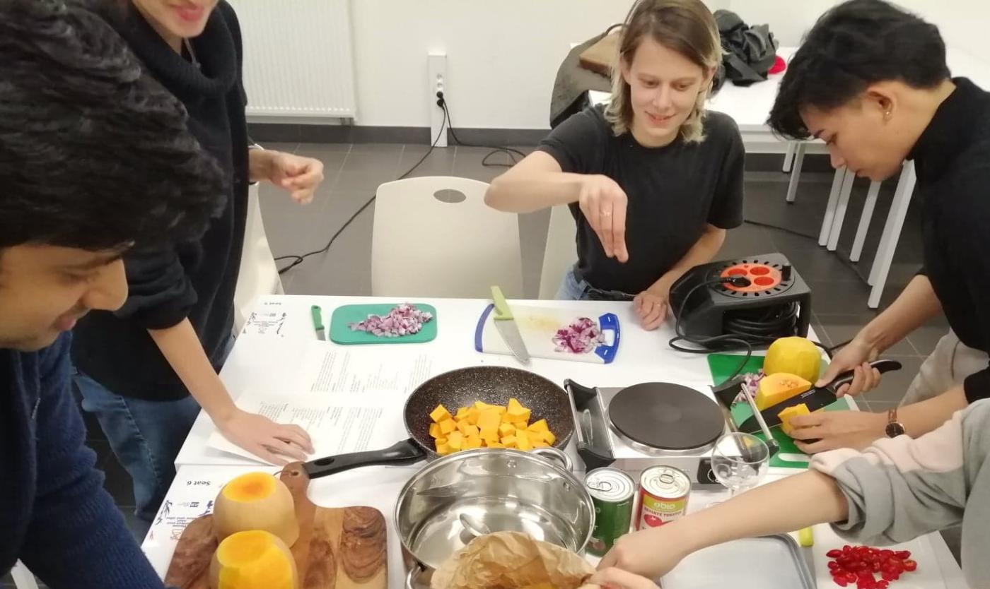 Four students preparing pumpkin soup together during a sustainable cooking workshop.