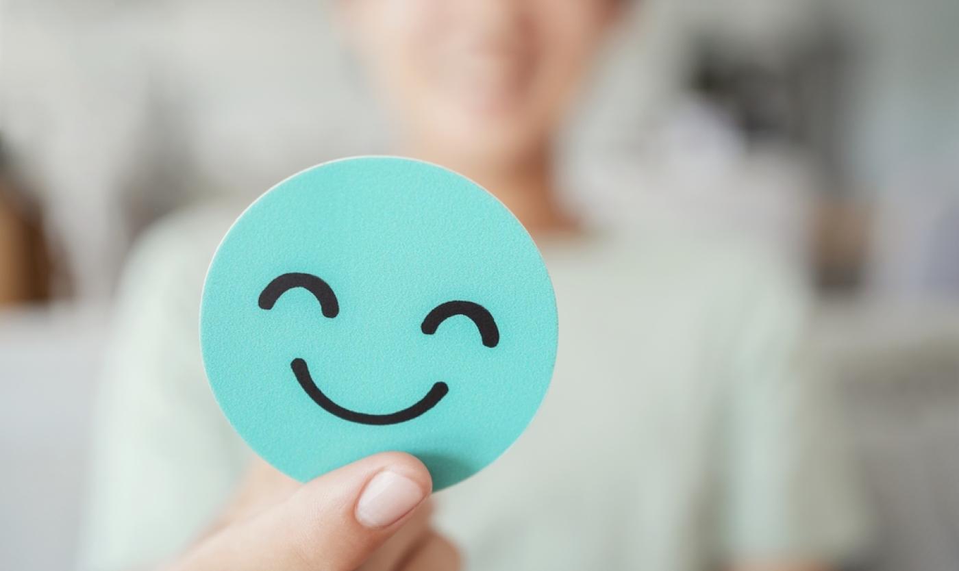 Vrouw met papieren lachend gezichtje in hand