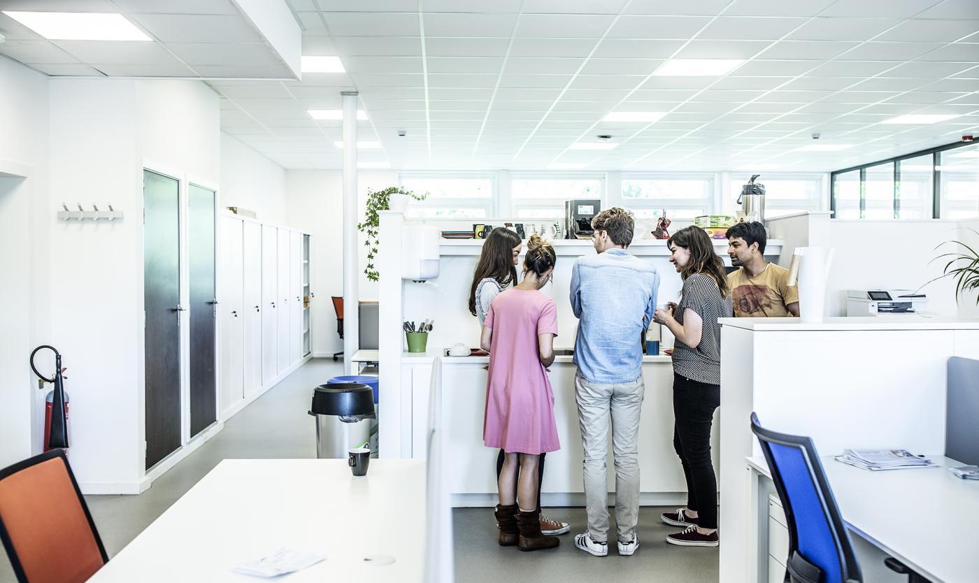 Collega's staan rond een tafel op kantoor ATP vacatures - M&O