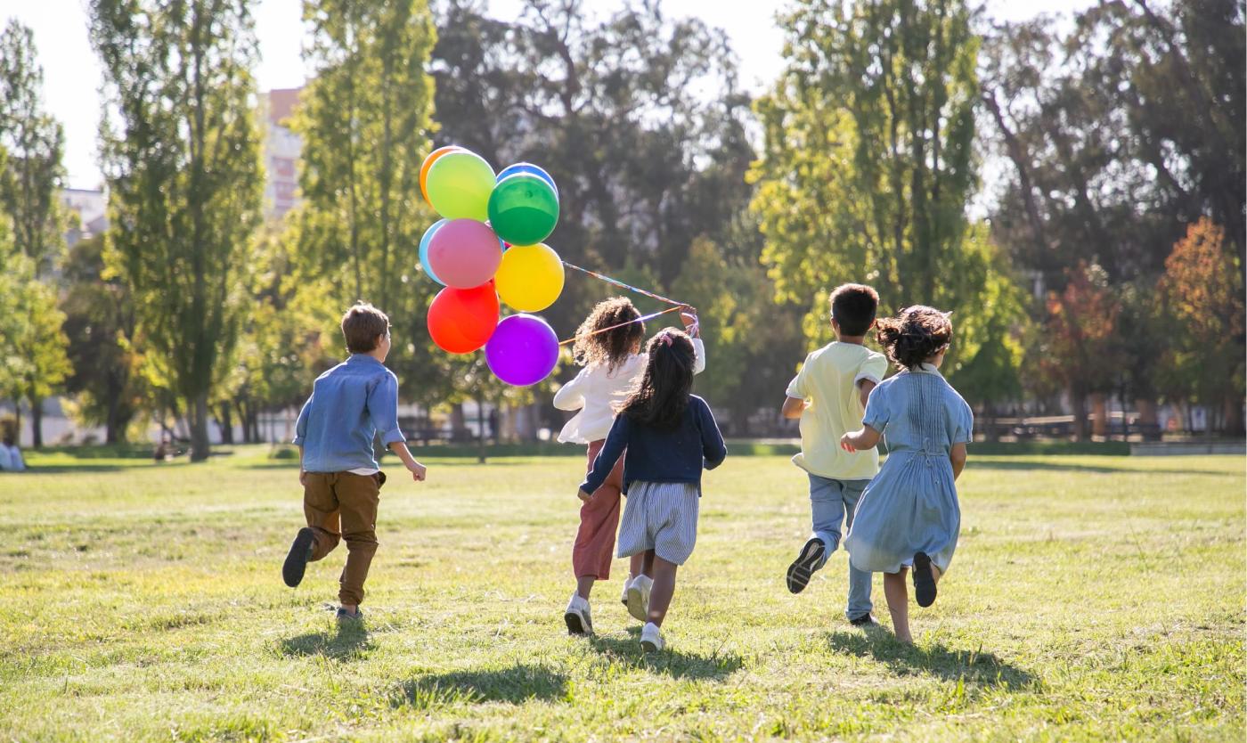 Kinderen lopen over grasveld met ballonnen