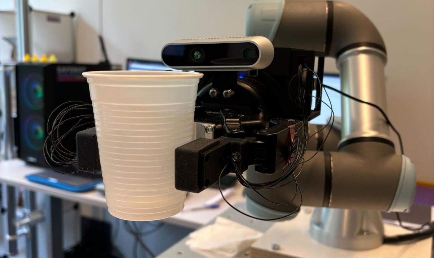 Robot met aanraaksensoren pakt plastic bekertje op