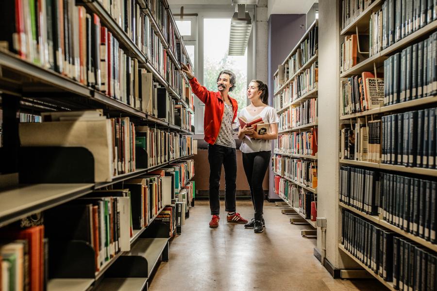 Studenten in bibliotheek aanwijzen een boekenkast op campus Etterbeek