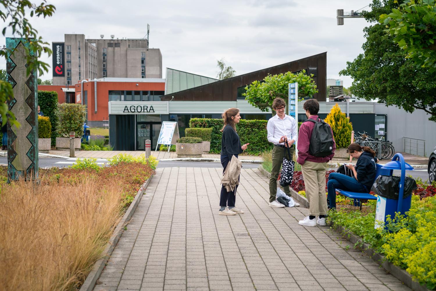 Lachende groep van studenten aan het praten voor het ingang van Agora op Campus Jette