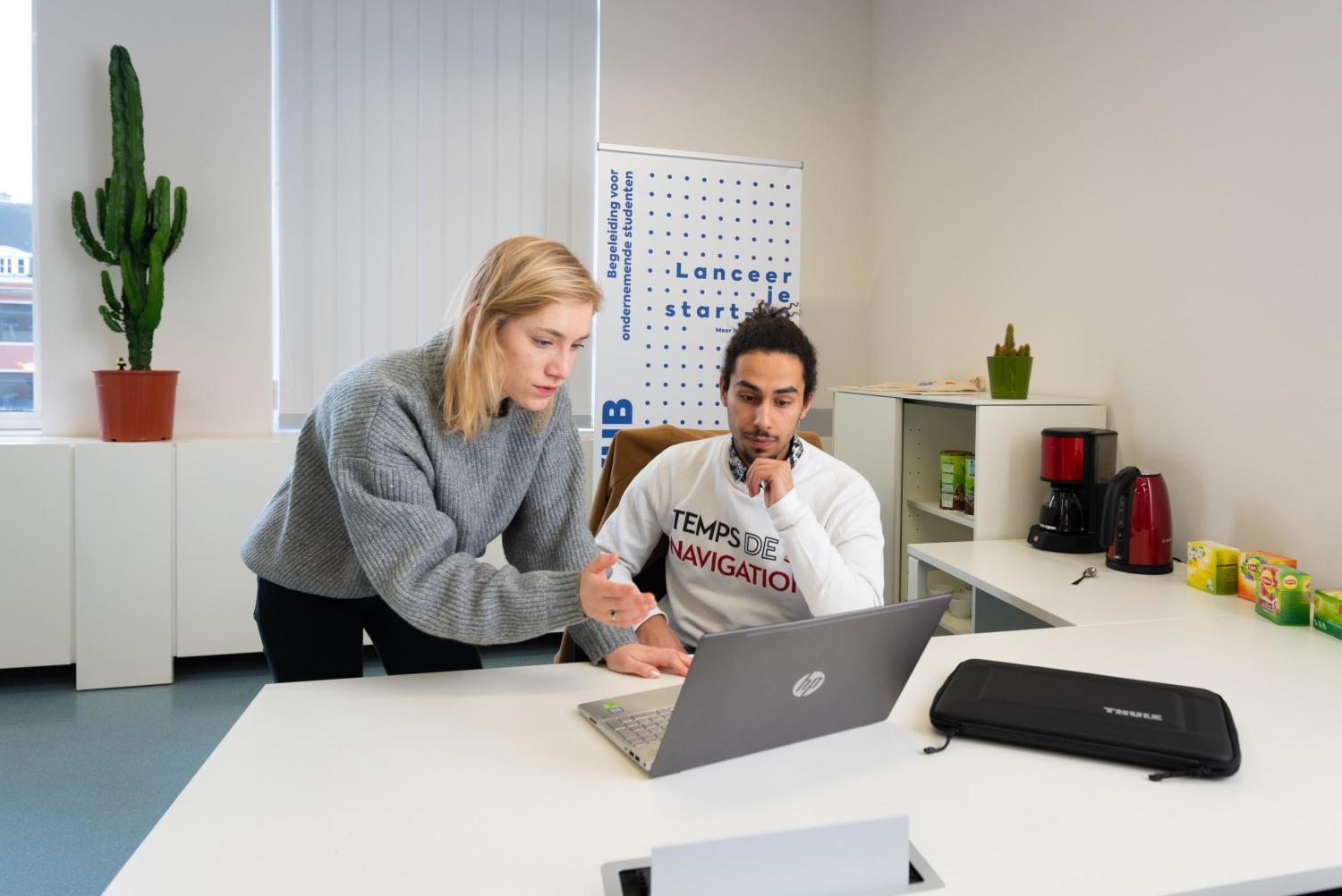 Student en studente kijken naar een scherm aan een bureau