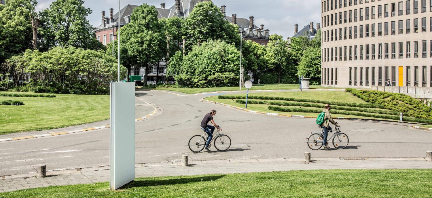 2022_Living Campus Walk_Koning fiets_Twee mannen op de fiets aan het Braemgebouw_Etterbeek_VUB