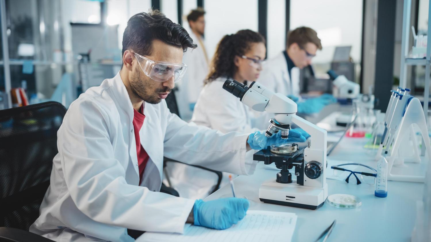 2022_Portret van Latijnse wetenschappers die onder microscoop kijken_Jonge biotechnologie specialisten met behulp van geavanceerde apparatuur_S_1922200196 Latijnse wetenschappers die onder microscoop kijken