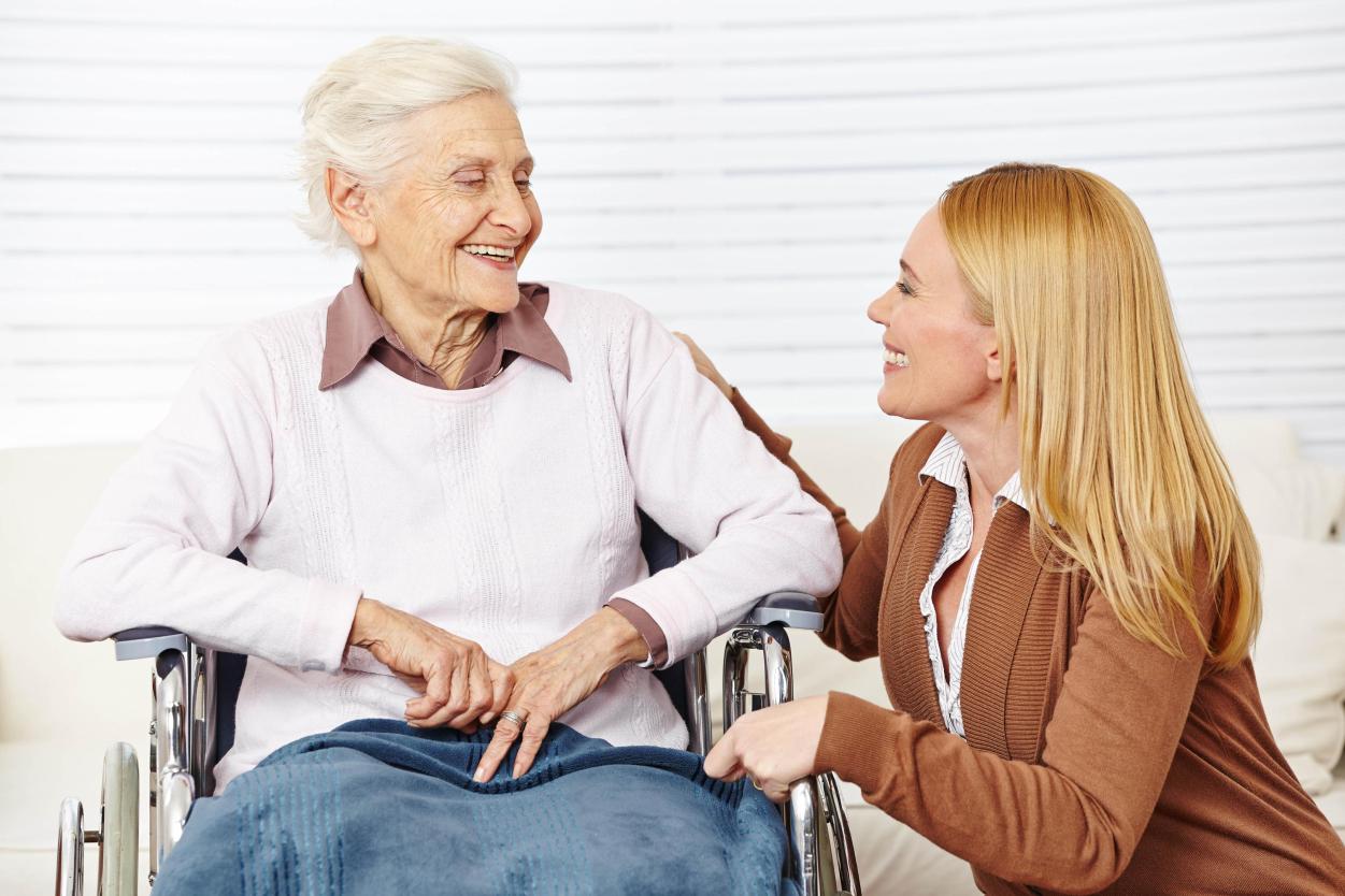 2022_Zorgverlener vrouw praten met senior burger in een rolstoel thuis_S_170076530
