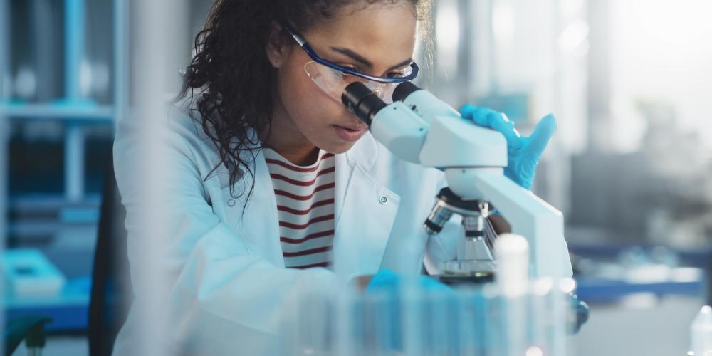 2022_Analyse van testmonster_Portret van etnische wetenschapper die onder microscoop kijkt_Medisch Wetenschapslaboratorium_S_1922200124 Medisch wetenschapslaboratorium met vrouwelijke wetenschapper