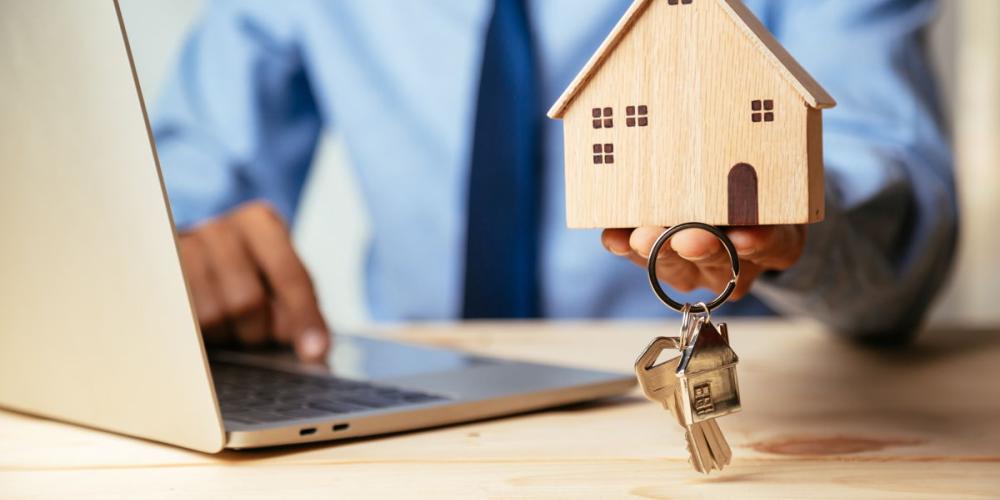 Makelaar Makelaar met modelhuis en sleutels in zijn hand