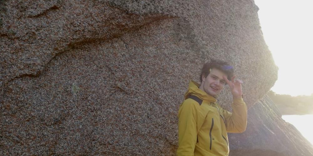 Hendrik De Pol standing with the sun behind him in front of a rocky background