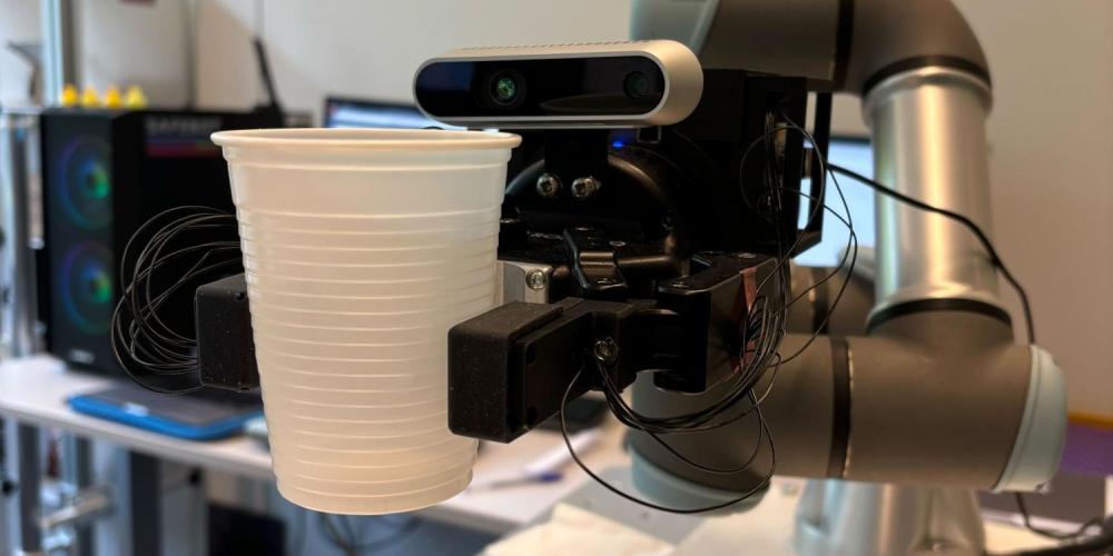 Robot met aanraaksensoren pakt plastic bekertje op