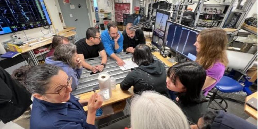 Low-Res_Team discussing preliminary results on the ship at the core table, image credit J Field-2.jpg